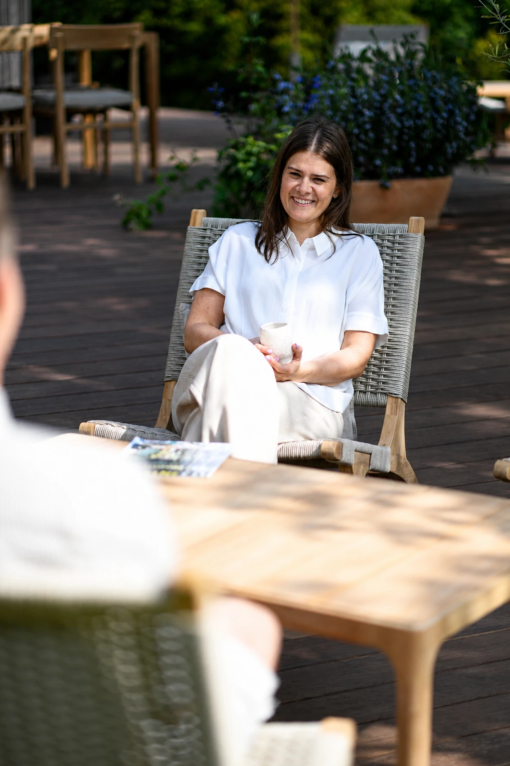Model siddende i Lumera lounge chair på en terrasse