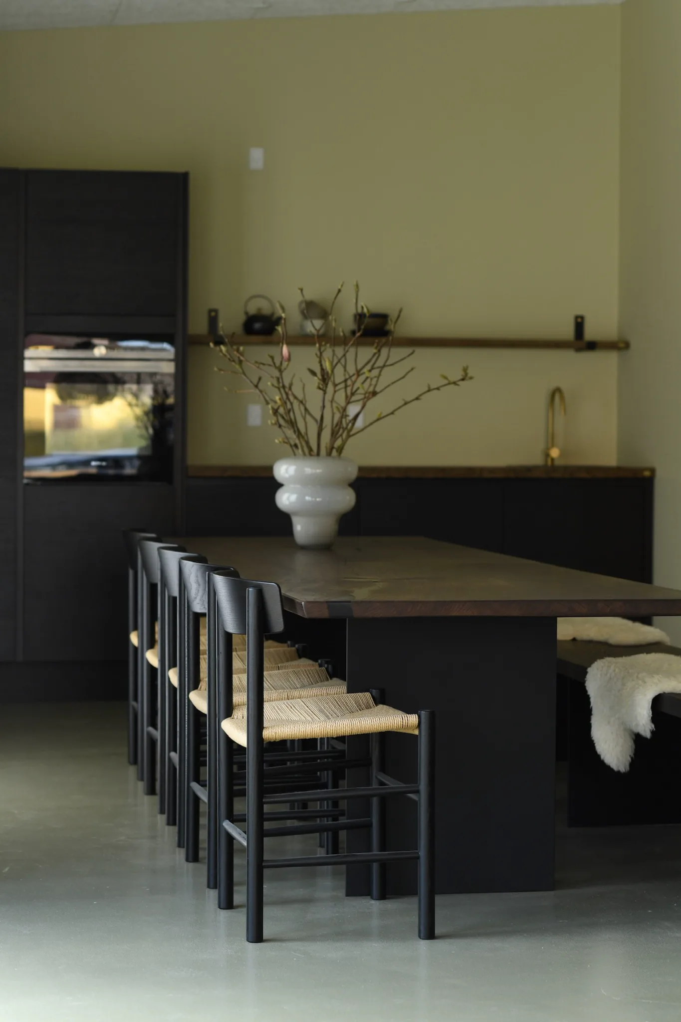 Mørkt plankebord med flettede stole i et moderne køkken